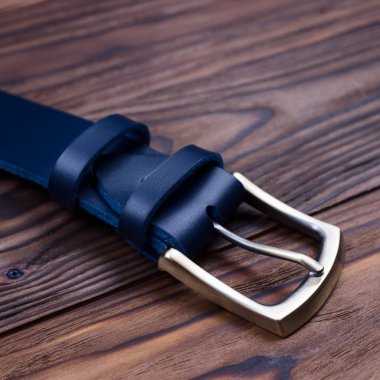 Ton mavisi el yapımı kemer tokası ahşap kaplamalı yakın plan üzerinde yatar. Yan görüş. İşadamı aksesuarlarının resmi..