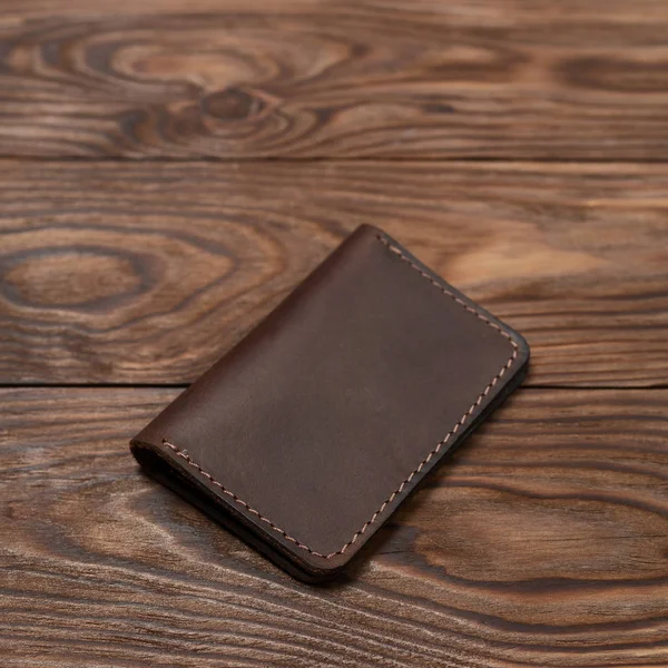 Brauner handgefertigter Kartenhalter aus geschlossenem Leder mit zwei Taschen liegt auf Holz — Stockfoto