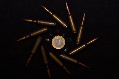 Siyah arka planda bir avro civarında bir sürü değerli taşlı tüfek mühimmatı. Savaşı para ve dünyanın sorunlarından biri için sembolize ediyor..