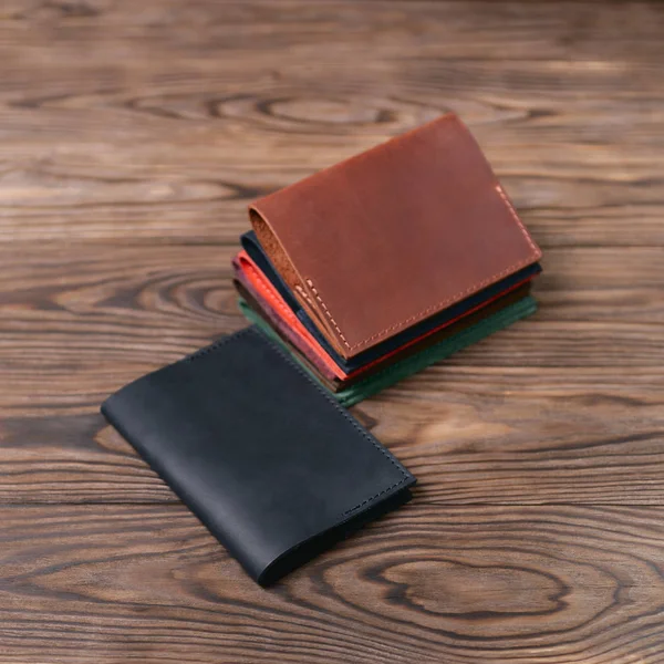 Six handmade leather passport covers on wooden textured background. Stock photo of luxury accessories.