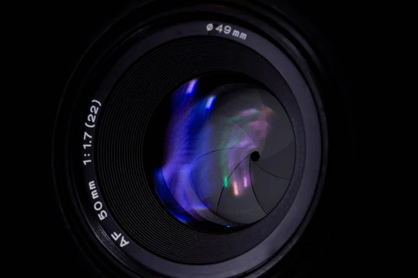 Lens aperture low light photo closeup. Colorful light traces on glass. Aperture blades is clean and dark. Stock photo isolated on black background.