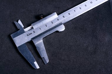 Vintage steel caliper on dark background. Scale in focus. Tool i