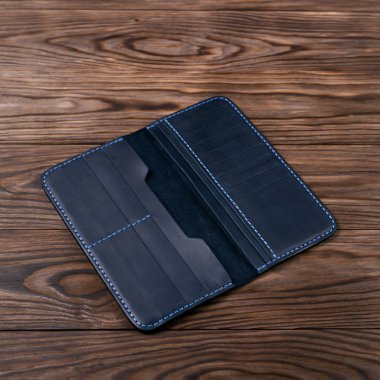 Ahşap desenli arka planda mavi renkli deri porte-monnaie. Çanta açıldı ve boş. Yan görüş. Lüks aksesuarların stok fotoğrafı.