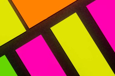 Siyah kağıda yeşil, sarı, turuncu ve mor renkli ofis etiketleri yapıştırdım. Hatırlatmak için ofis noteri. Siyah kağıda izole edilmiş..