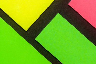 Siyah kağıda yeşil, sarı ve gül renkli ofis etiketleri yapıştırdım. Hatırlatmak için ofis noteri. Siyah kağıda izole edilmiş..