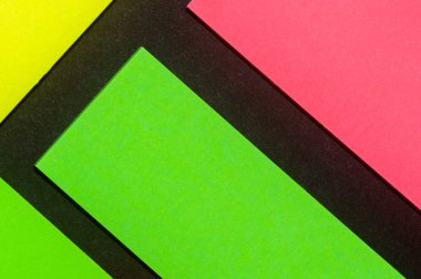 Siyah kağıda yeşil, sarı ve gül renkli ofis etiketleri yapıştırdım. Hatırlatmak için ofis noteri. Siyah kağıda izole edilmiş..