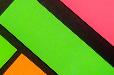 Siyah kağıda yeşil, turuncu ve gül renkli ofis etiketleri yapıştırdım. Hatırlatmak için ofis noteri. Siyah kağıda izole edilmiş..