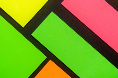 Siyah kağıda yeşil, sarı, turuncu ve gül renkli ofis etiketleri yapıştırdım. Hatırlatmak için ofis noteri. Siyah kağıda izole edilmiş..