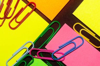 Renkli ofis etiketleri üzerine ataçlar siyah kağıt üzerine yapıştırmalar.