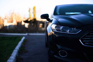 Modern araba farları çekiliyor. Güzel araba gözleri. Arabanın yarısı fotoğrafta, geçmişi bulanık. Görüntüyü kapat. Saldırgan araba gözleri..