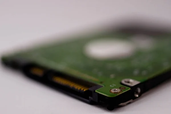 2.5mm laptop HDD on white blurred background. A lot of space on photo is defocused or have soft focus.