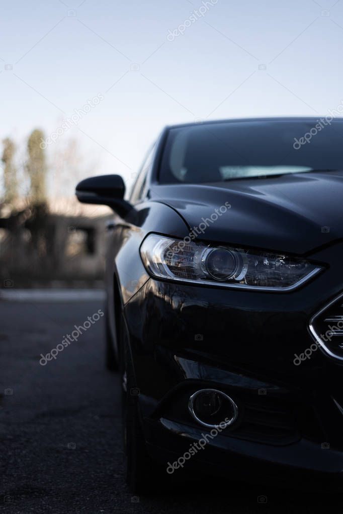 Modern car headlamps shot. Nice car eyes. Half of car on photo, blurred background. Cose up view. Aggressive car eyes.