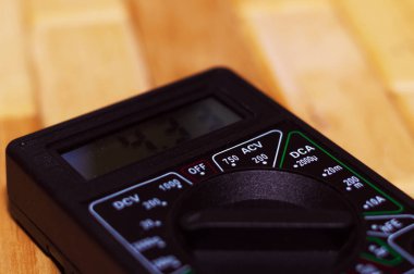 Ahşap zeminde dijital ölçüm multimetresi. 4.33V veya tam şarjlı pil gösteriyor. Voltmetre, ampermetre, ohmmetre içerir.