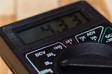 Ahşap zeminde dijital ölçüm multimetresi. 4.33V veya tam şarjlı pil gösteriyor. Voltmetre, ampermetre, ohmmetre içerir.