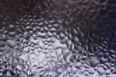 Cam pencereye su damlaları düşer. Arka planda bulanıklık olur. Makroda damlalar. Pencereye yakın mesafede yoğunlaş. Islak hava.