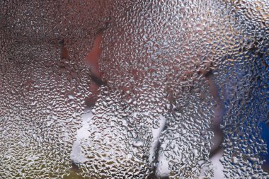 Cam pencereye su damlaları düşer. Arka planda bulanıklık olur. Makroda damlalar. Pencereye yakın mesafede yoğunlaş. Islak hava.