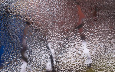 Cam pencereye su damlaları düşer. Arka planda bulanıklık olur. Makroda damlalar. Pencereye yakın mesafede yoğunlaş. Islak hava.