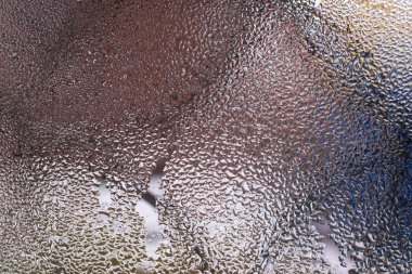 Cam pencereye su damlaları düşer. Arka planda bulanıklık olur. Makroda damlalar. Pencereye yakın mesafede yoğunlaş. Islak hava.