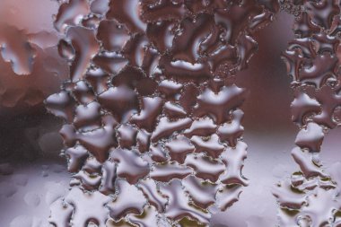 Cam pencereye su damlaları düşer. Arka planda bulanıklık olur. Makroda damlalar. Pencereye yakın mesafede yoğunlaş. Islak hava.