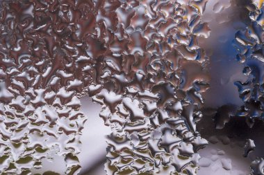 Cam pencereye su damlaları düşer. Arka planda bulanıklık olur. Makroda damlalar. Pencereye yakın mesafede yoğunlaş. Islak hava.