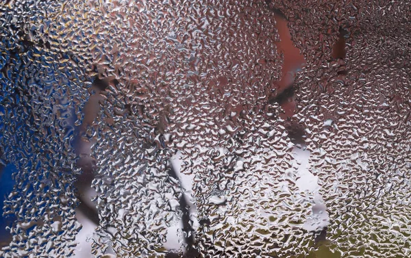 Cam pencereye su damlaları düşer. Arka planda bulanıklık olur. Makroda damlalar. Pencereye yakın mesafede yoğunlaş. Islak hava.