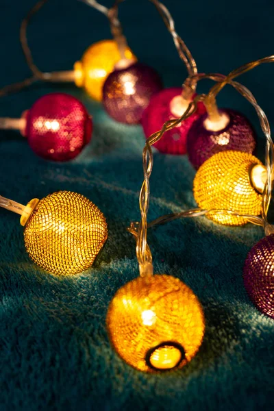 Battery garland with metallic grid balls on blue blanket. Closeup view with blurred background.