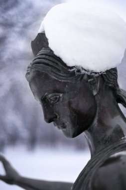 Kar parkında bronz bir kadın heykeli. Bulanık arkaplan ile yakın plan.
