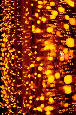 Cam camda dikey Noel çelengi duvarı var. Işık turuncu ve odağını kaybetmiş. Bulanık arkaplan, yeni yıl havası.