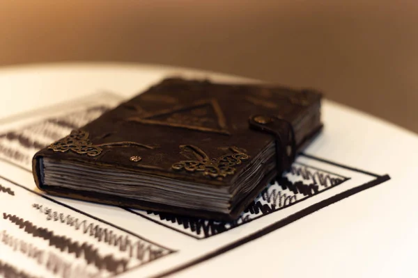 Handmade magic notebook with tower symbol on cover. Leather cover and handmade sheets inside. Very blurred background with soft focus on notebook.