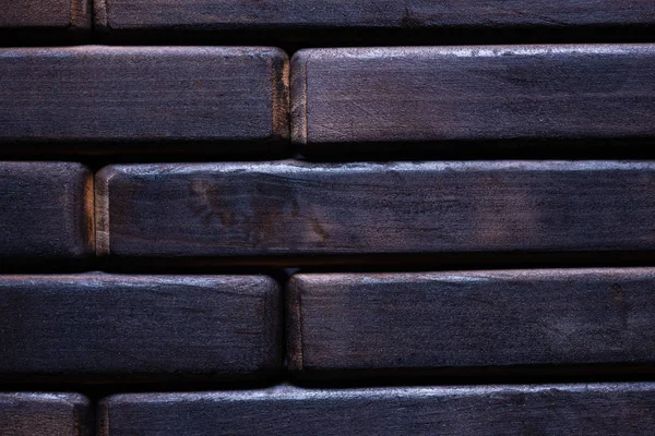 Dark black wooden background. Floor contains wooden bricks. Closeup view.