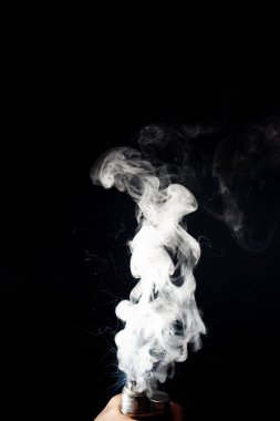 Adam eli vape tutuyor. Vape bulutlar siyah arka üzerinde bobinden sıçrama