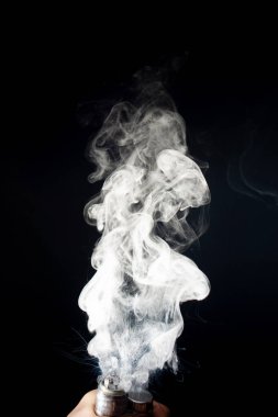 Adam eli vape tutuyor. Vape bulutlar siyah arka üzerinde bobinden sıçrama