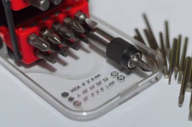 Kutuda parça tutucu ve beyaz arkaplanda bir sürü araç biti. Yakın çekim görüntüsü. Plastik kutuda kırmızı element.