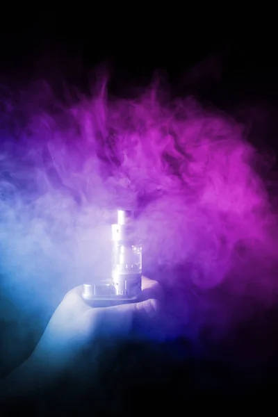 Male hand holds vape in thick vape fog or smoke. Vape clouds around hand with vape on black background. — Stock Photo, Image