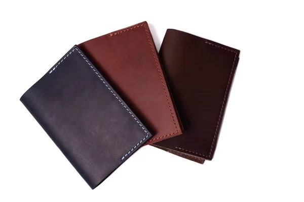 Três capas de passaporte de couro artesanal isoladas em fundo branco. Vista de perto. As capas são azul escuro, vermelho, marrom e fechado . — Fotografia de Stock