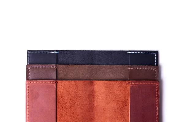 Three handmade leather passport covers stack isolated on white background. Closeup view. Covers are dark blue, red, brown and opened. — Stock Photo, Image