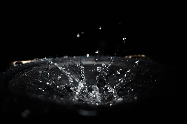 The splash of water drops in loudspeaker on black background. Pe