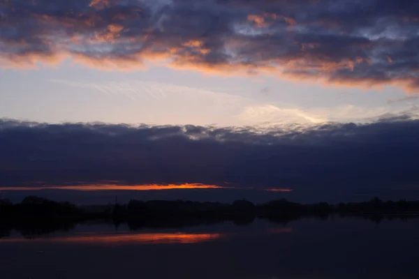 Roter Abendsonnenuntergang über dem See oder Fluss. lila und blauer Clou — Stockfoto