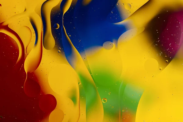 Abstract oil spots in motion on water on blurred yellow backgrou — Stock Photo, Image