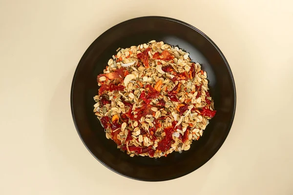 En välsmakande saltgranola med peppar i svart skål på baige bakgroun — Stockfoto