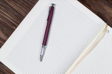 Günlük planlayıcıyı mor dolma kalemle ahşap arka planda aç. Kopyalama şablonu ve markalaşma modellemesi.