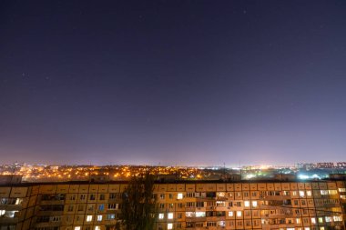 Bir sürü yıldız ve takımyıldızlı gece yıldızlı şehir manzarası. Yüksek binanın çatısından görüntüle.