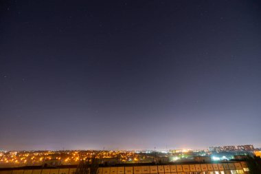 Bir sürü yıldız ve takımyıldızlı gece yıldızlı şehir manzarası. Yüksek binanın çatısından görüntüle.