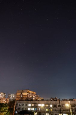 Bir sürü yıldız ve takımyıldızlı gece yıldızlı şehir manzarası. Yüksek binanın çatısından görüntüle.