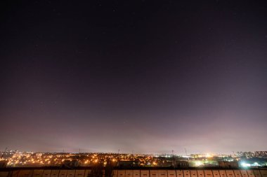 Bir sürü yıldız ve takımyıldızlı gece yıldızlı şehir manzarası. Yüksek binanın çatısından görüntüle.