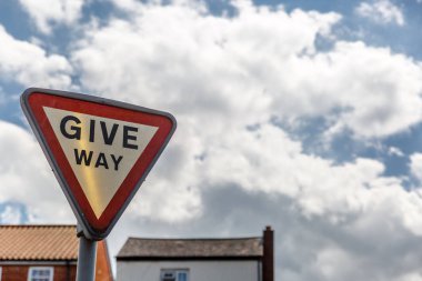 Bazı evler ve arka planda, İngiltere'de güzel bir gökyüzü ile yol verme işareti
