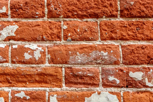 Wall of large orange bricks with white paint spots