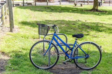 Mavi bisiklet görünümünü bir parkın ortasında bir metal çapa bağlı
