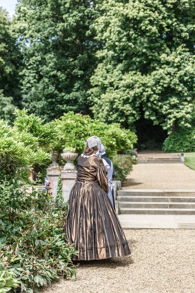 Dönemde giymiş kadın Blickling Hall, manor house Aylsham Norfolk, İngiltere'de ilçe kuzeyinde Blickling Köyü içinde bahçeleri biri size yürür