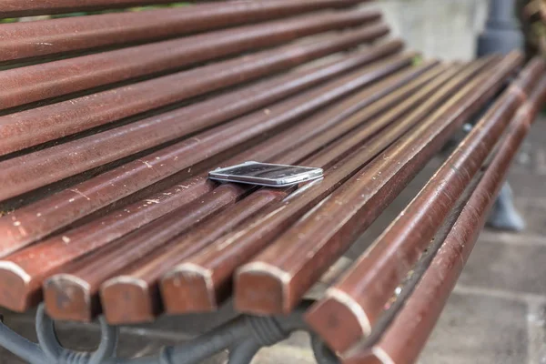 Mobile phone on top of a wooden bench in a park